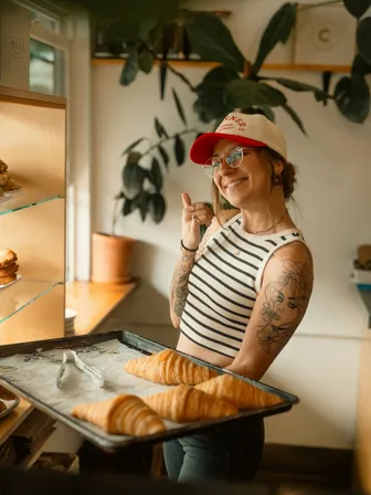 A baker presenting fresh croissants