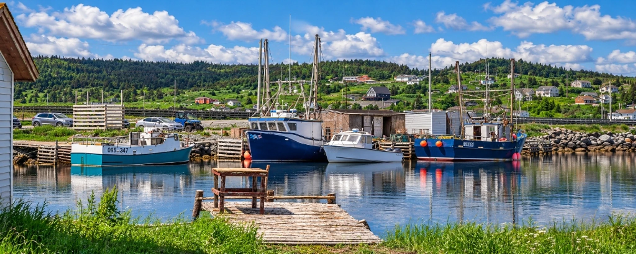 Fishing boats moored in a harbour, with a wooden wharf in the foreground.