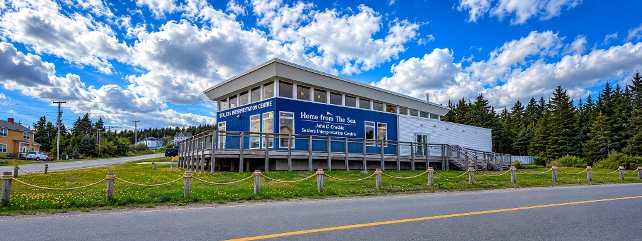 A blue interpretation centre with a wooden deck and access ramp beside a grassy lawn.