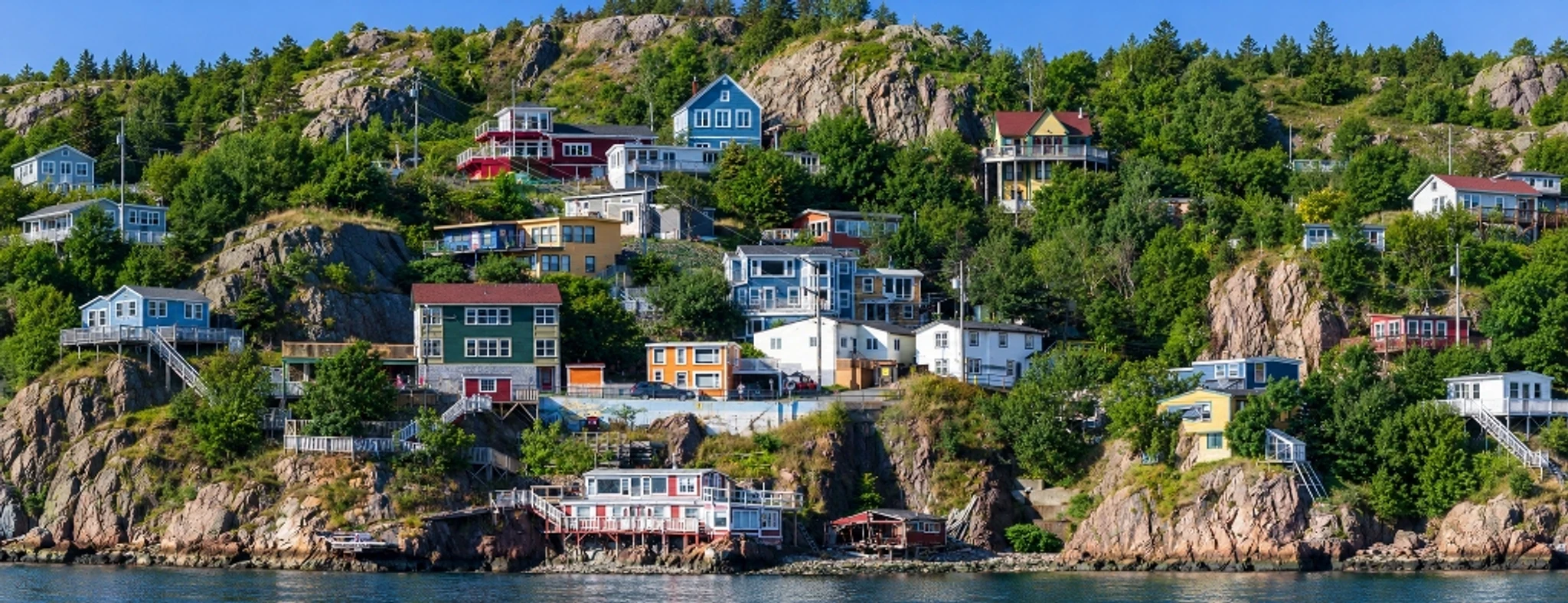 Colourful hillside homes among trees and rocky slopes above the water.