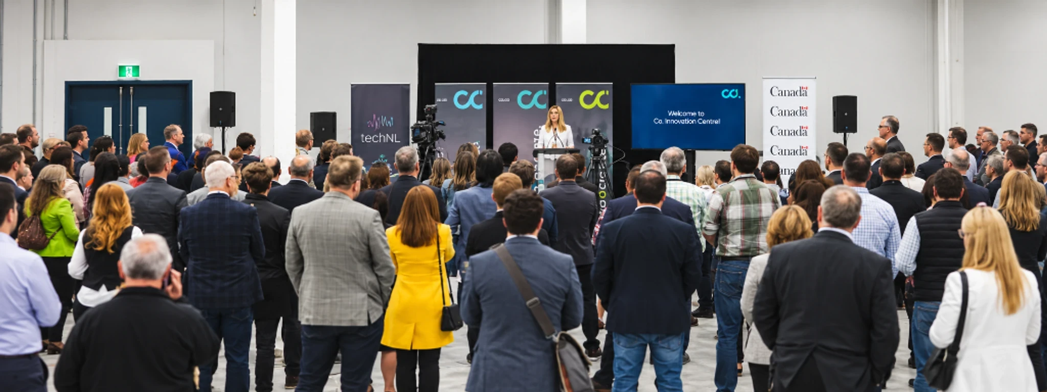 An audience facing a speaker and presentation screens at a technology event.